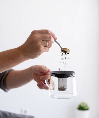 Erkek eli yakın çaydanlığa çay yaprakları döküyor.