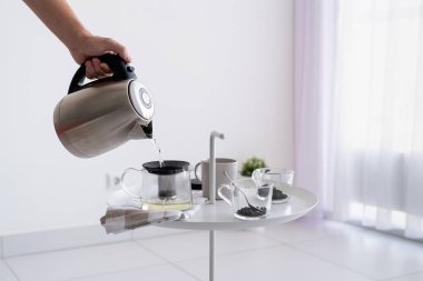 Çay yapıyorum. Kahve masasını kapat ve çaydanlığı tutan adam çay yapmak için sıcak su dök.
