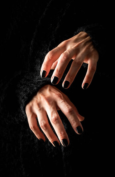 Happy Halloween concept. Creepy woman Halloween hands with black nails on dark background