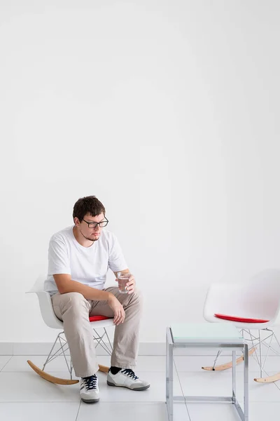 Mental health and healthcare. Young depressed man with headache sitting on the chair