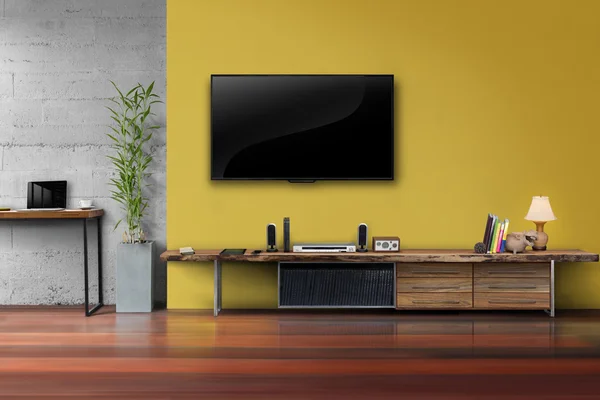 TV sarı duvarda ahşap masa medya mobilya ile açtı.