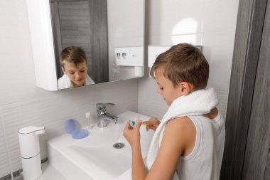 Genç bir çocuk temiz plastik diş hizasını dikkatlice temizler ya da diş fırçasıyla banyo lavabosunun üstüne diş macunu koyar. Uygun ortodontik hijyen ve sağlık rutinine odaklanır.