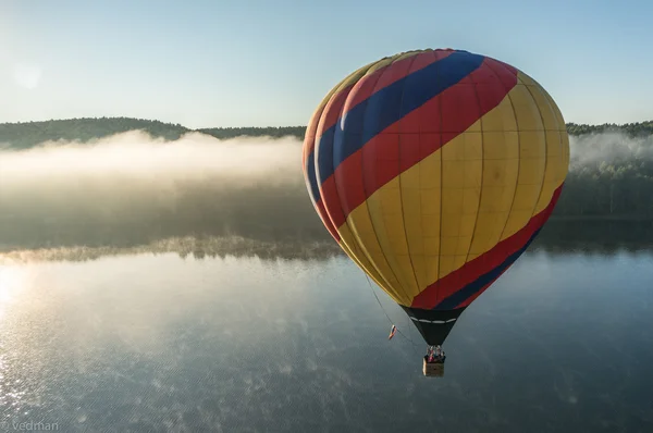 Balão de ar quente voando acima do lago na névoa — Fotografia de Stock