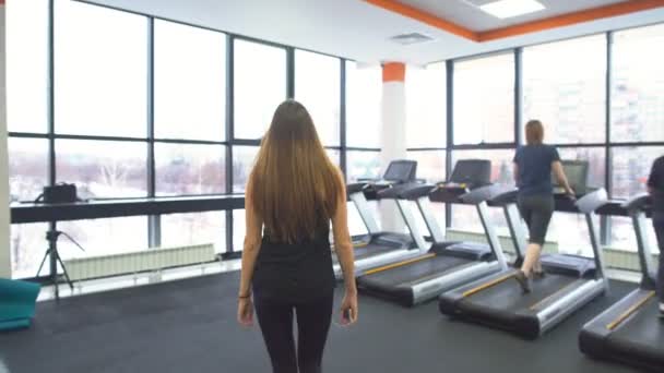 Девушка тренируется на беговой дорожке в спортзале — стоковое видео