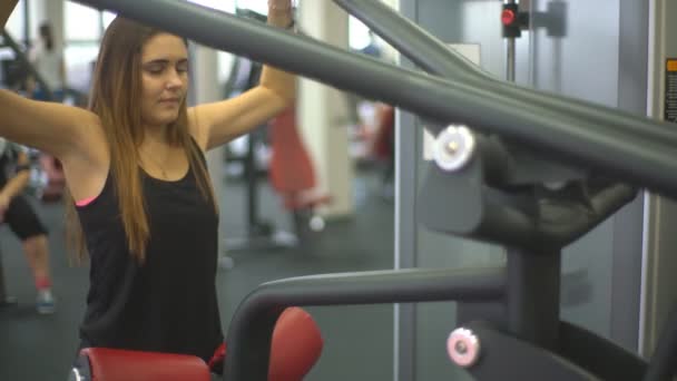 Beautiful young woman doing exercises to strengthen the shoulder simulator — Stock Video