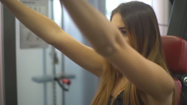 Молодая симпатичная девушка делает упражнения на тренажере — стоковое видео