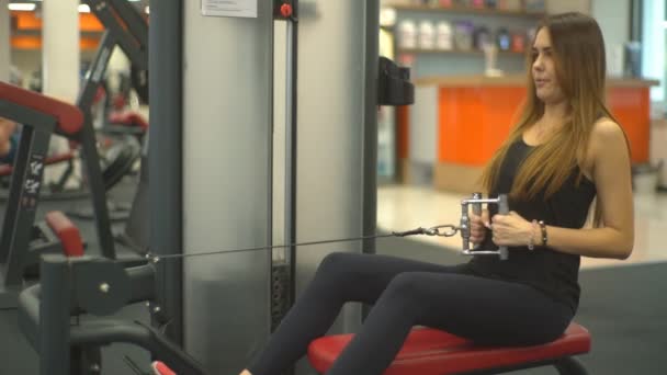 Jovem menina bonita fazendo exercício em um simulador nos músculos das costas — Vídeo de Stock