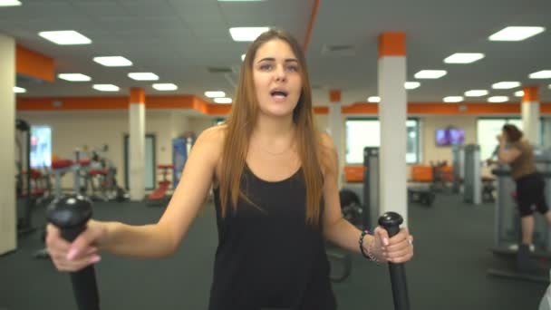 Slanke onherkenbaar vrouw wandelingen elliptische trainer geïsoleerd — Stockvideo