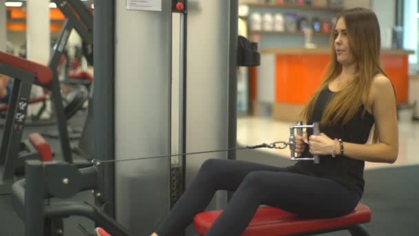 Joven bonita chica haciendo ejercicio en un simulador en los músculos de la espalda — Vídeo de stock