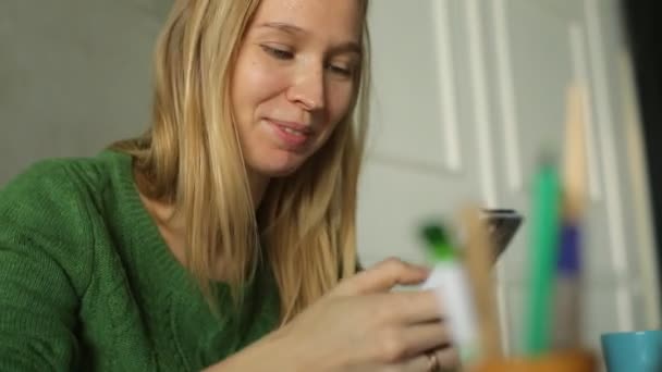 Dizüstü bilgisayar ve kullanma smartphone ile oturan güzel genç kadın — Stok video
