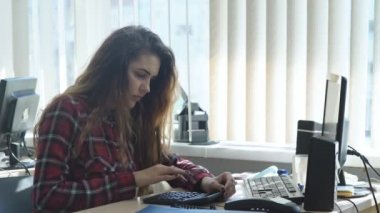 güzel kız ofiste çalışıyor ve hesap makinesi kullanır