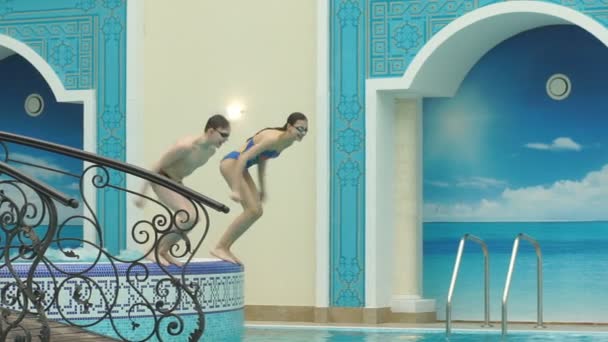 Boy and girl jumping into the pool — Stock Video