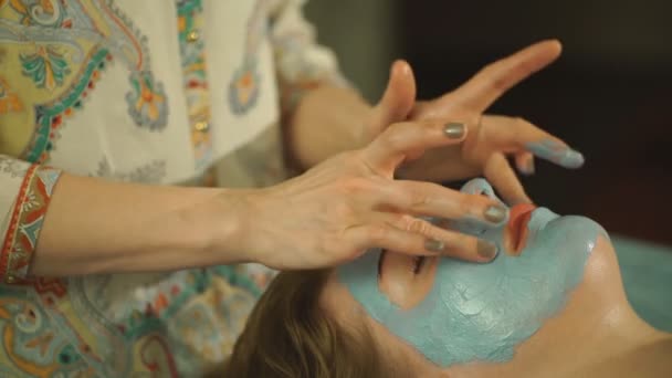Kvinnan gör en ansiktsmask av lera — Stockvideo