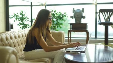 bir deri kanepede oturan ve bir bilgisayarda çalışma güzel iş kadını