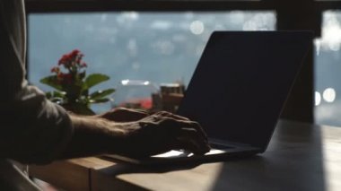 bir adam bir kafede Rıhtımlar üzerinde bir dizüstü bilgisayar kullanarak