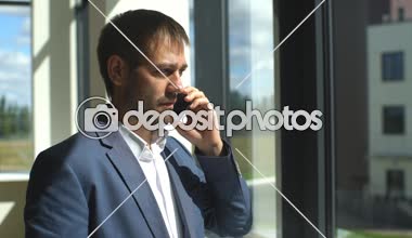 ofis penceresinde yakınındaki telefonda konuşurken başarılı genç işadamı