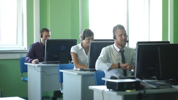 Colegas de negócios com fones de ouvido usando computadores na mesa do escritório m dern — Vídeo de Stock