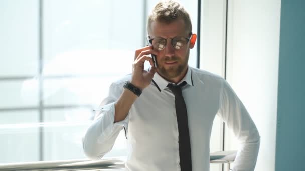 Jonge zakenman praten aan de telefoon in de lobby van het Bureau — Stockvideo