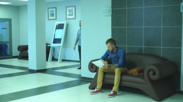 Een man passeert de documenten naar een collega in de lobby van het Bureau — Stockvideo