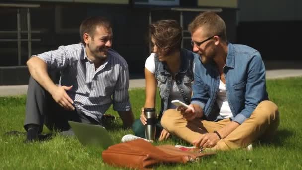Tres estudiantes sentados en el césped — Vídeos de Stock