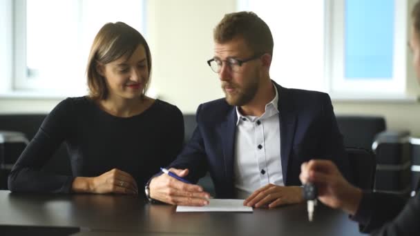 Dwóch mężczyzn siedzi przy biurku i drżenie rąk, podczas gdy młoda kobieta patrzy na nich i uśmiechnięty — Wideo stockowe