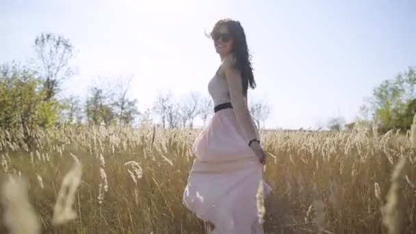 Красивая девушка выходит на поле в юбке замедленного действия — стоковое видео