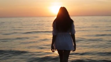 bir kız günbatımı yavaş denize girer