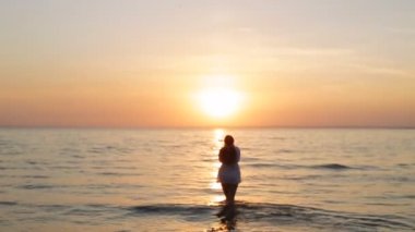 bir kız günbatımı yavaş denize girer