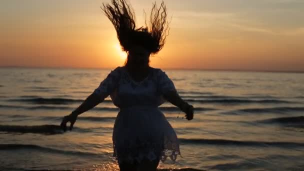 Vrouw silhouet dansen en springen op sunset beach — Stockvideo