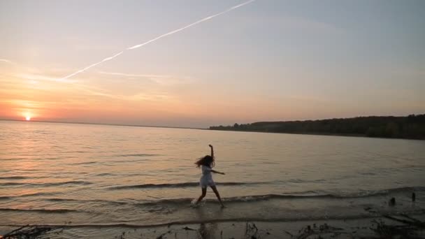 Νεαρή γυναίκα που τρέχει στις ακτές της θάλασσας στο ηλιοβασίλεμα αργή κίνηση — Αρχείο Βίντεο