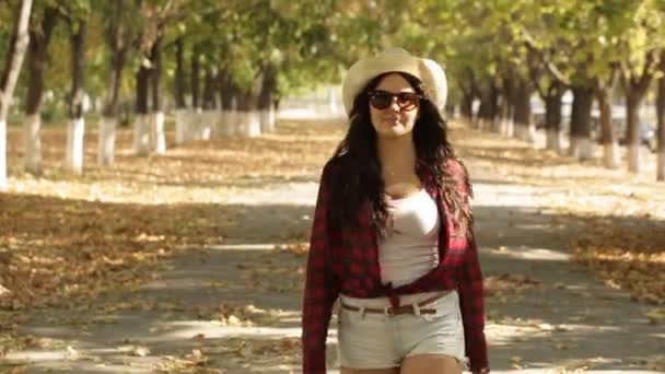 Chica camina en el callejón de otoño a la cámara y se quita las gafas — Vídeos de Stock