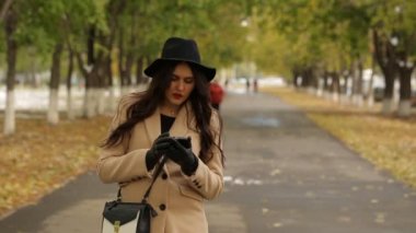 Bej bir palto Sokağı'nda smartphone kullanarak içinde kız