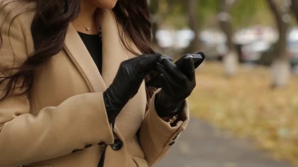 Flicka i i beige kappa med smartphone på street — Stockvideo
