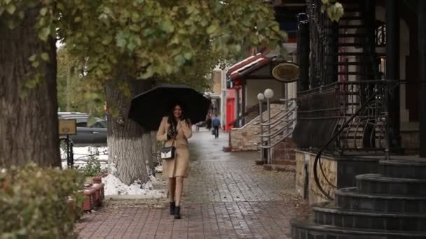 Menina sob guarda-chuva andando e falando ao telefone — Vídeo de Stock