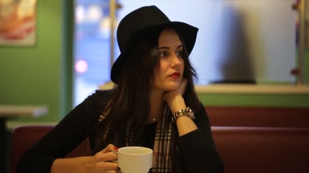 Young woman sitting in cafe and dreams of a beautiful — Stock Video