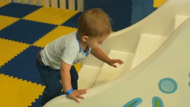 Гарненький хлопчик грає на іграшковому пагорбі на дитячому майданчику — стокове відео