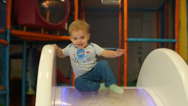 Menino bonito brincando na colina de brinquedo no playground — Vídeo de Stock