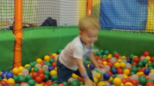 Lachende jongetje spelen in kleurrijke ballen — Stockvideo
