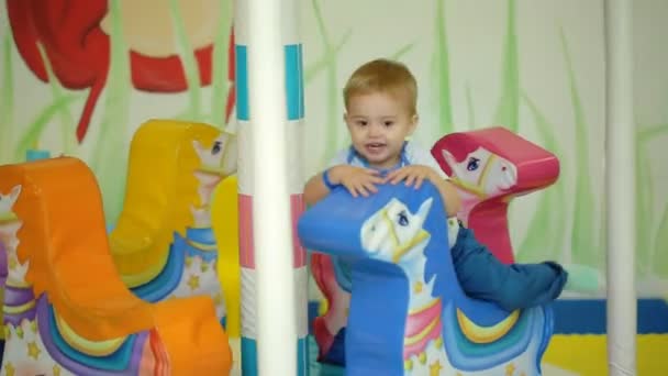 Sonriente niño montando un carrusel de caballo de juguete — Vídeos de Stock