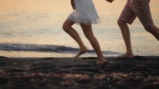 Feliz pareja está corriendo a lo largo de la orilla al amanecer — Vídeos de Stock