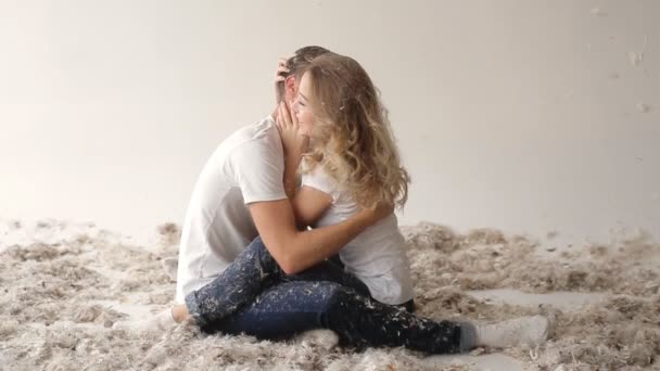 Молодая пара борется подушки в фотостудии, на белом фоне — стоковое видео