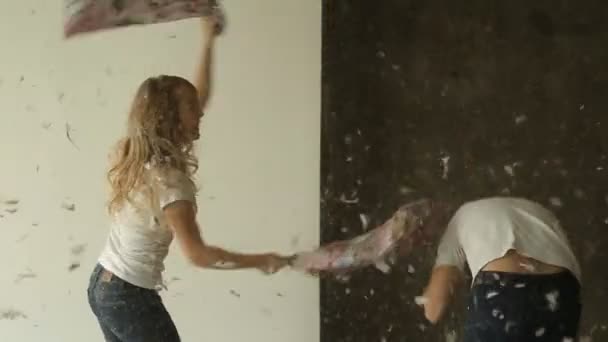 Молодая пара борется подушки в студии — стоковое видео