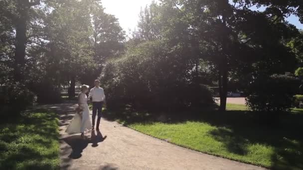Наречений і наречений виходять у парк на відкритому повітрі — стокове відео
