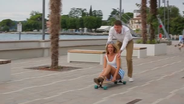 Mladý šťastný pár v lásce sedící na skateboardu — Stock video