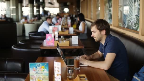 Серйозна людина з ноутбуком в кафе — стокове відео