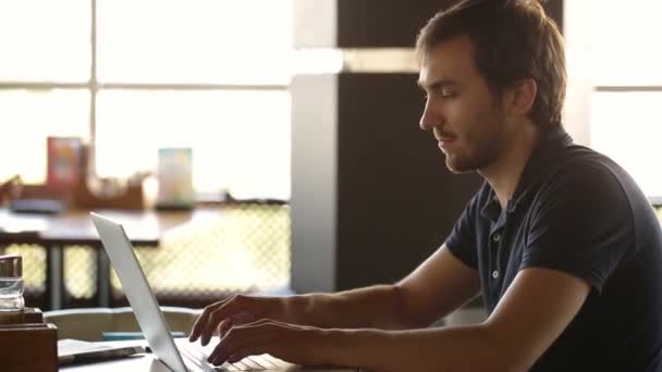 Een man zitten in een cafe en werken op een laptop — Stockvideo