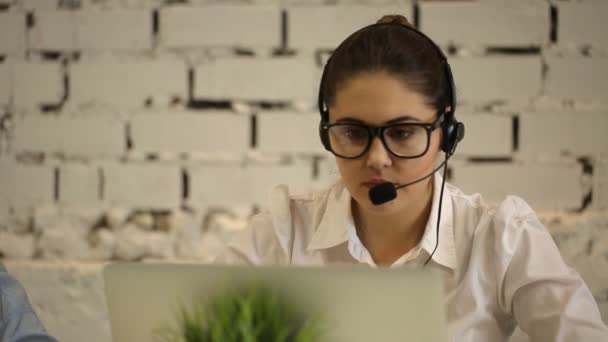 Woman typing on computer and talking on the phone number — Stock Video