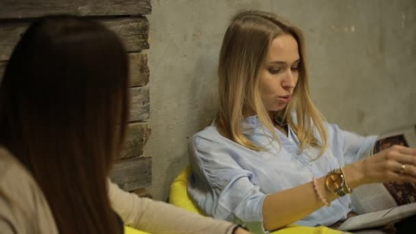 Menina conversando com seu amigo e lendo uma revista — Vídeo de Stock