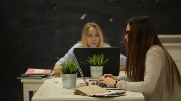 Две девушки сидят в офисе и разговаривают — стоковое видео