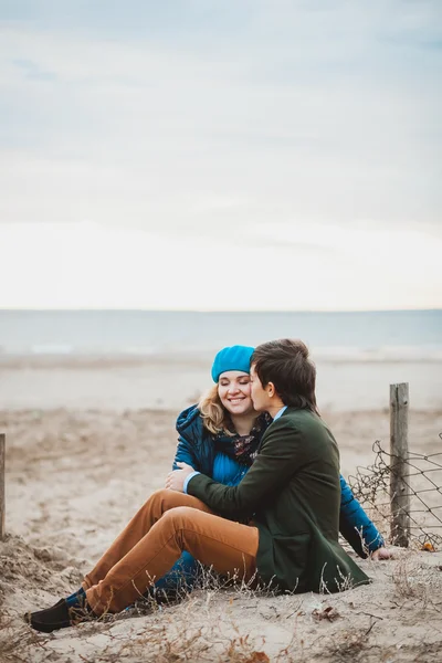 Молодая пара сидит и позирует на пляже осенью — стоковое фото